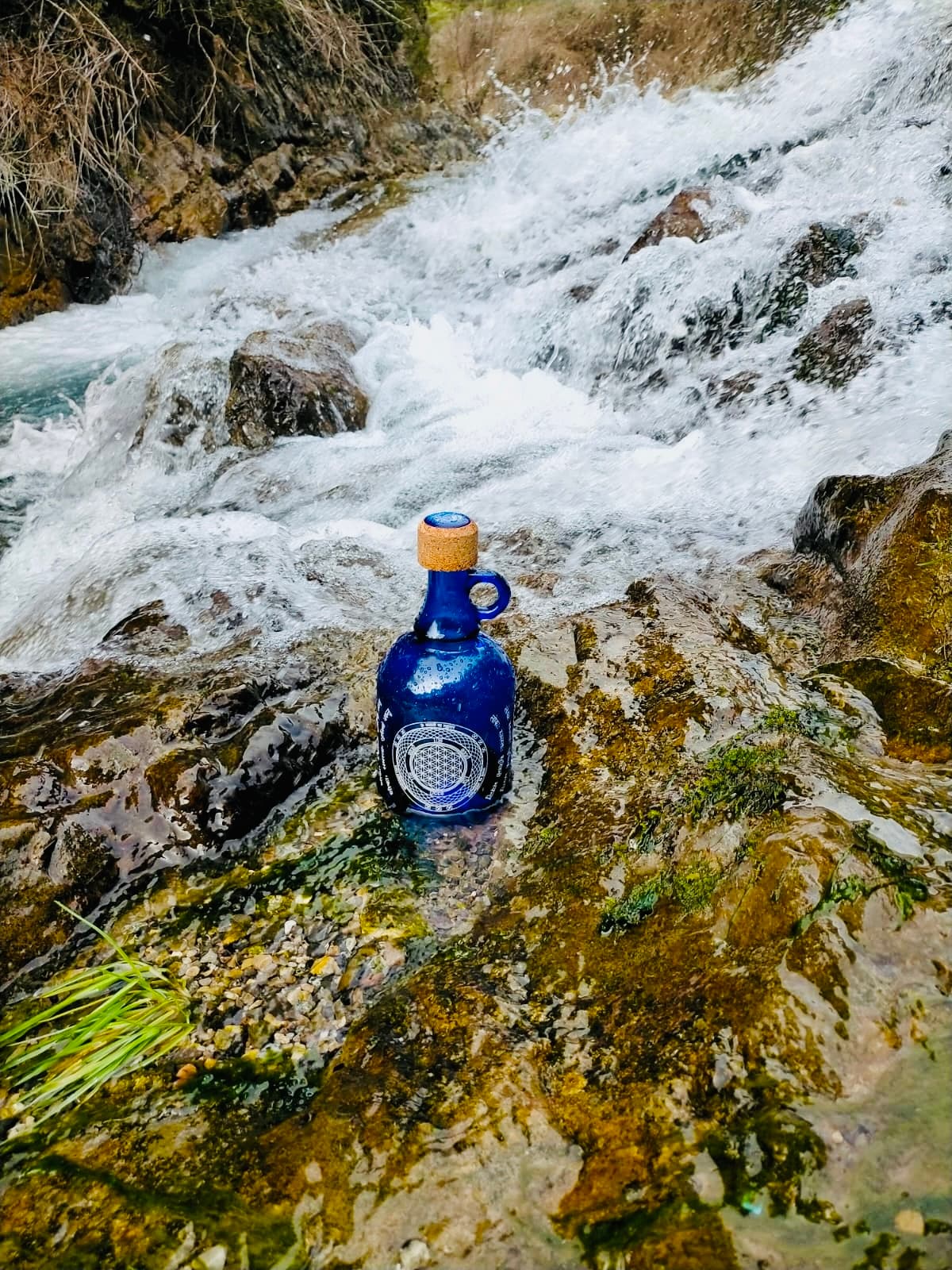 Botella Devi de cristal cobalto en un manantial de agua viva